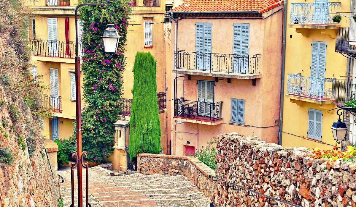 beautiful cobblestone street in cannes with some pastel colored houses in the background