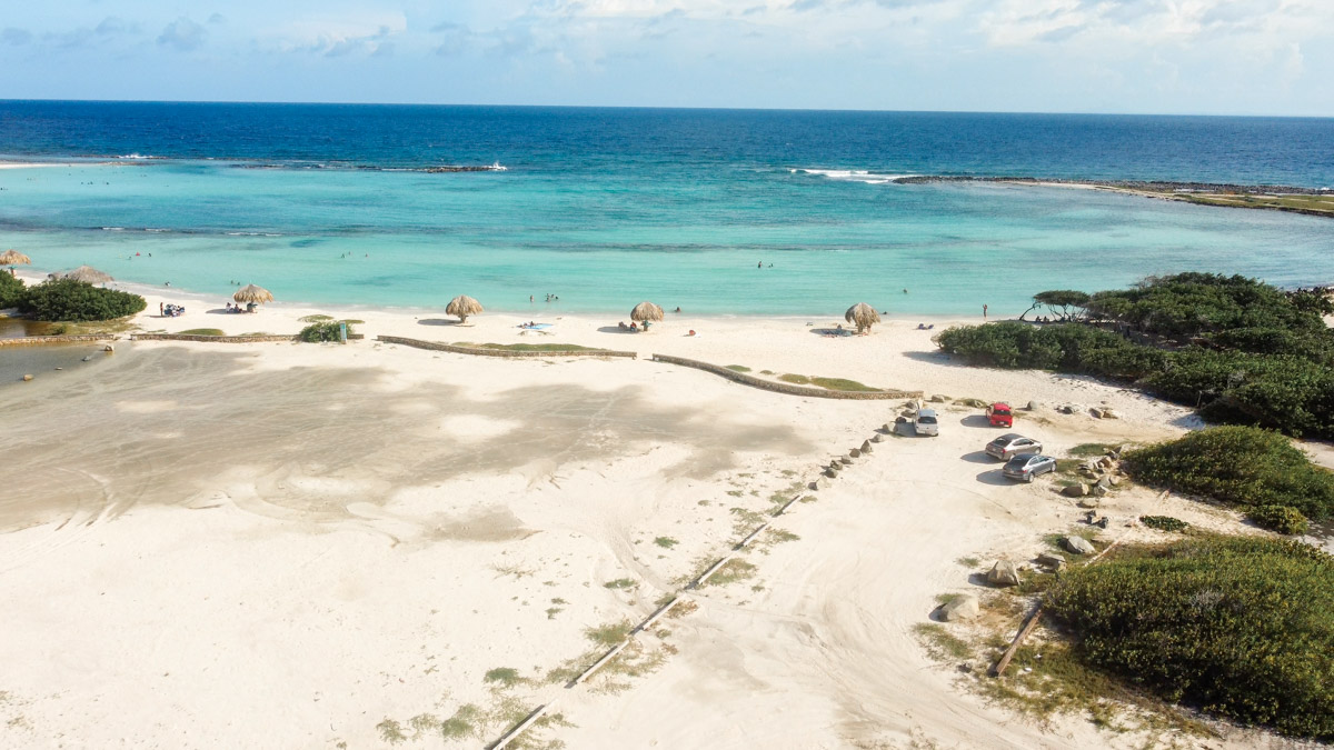 Aerial view of a coastal area with clear blue waters, sandy beaches, and sparse greenery Baby Beach in Aruba. 