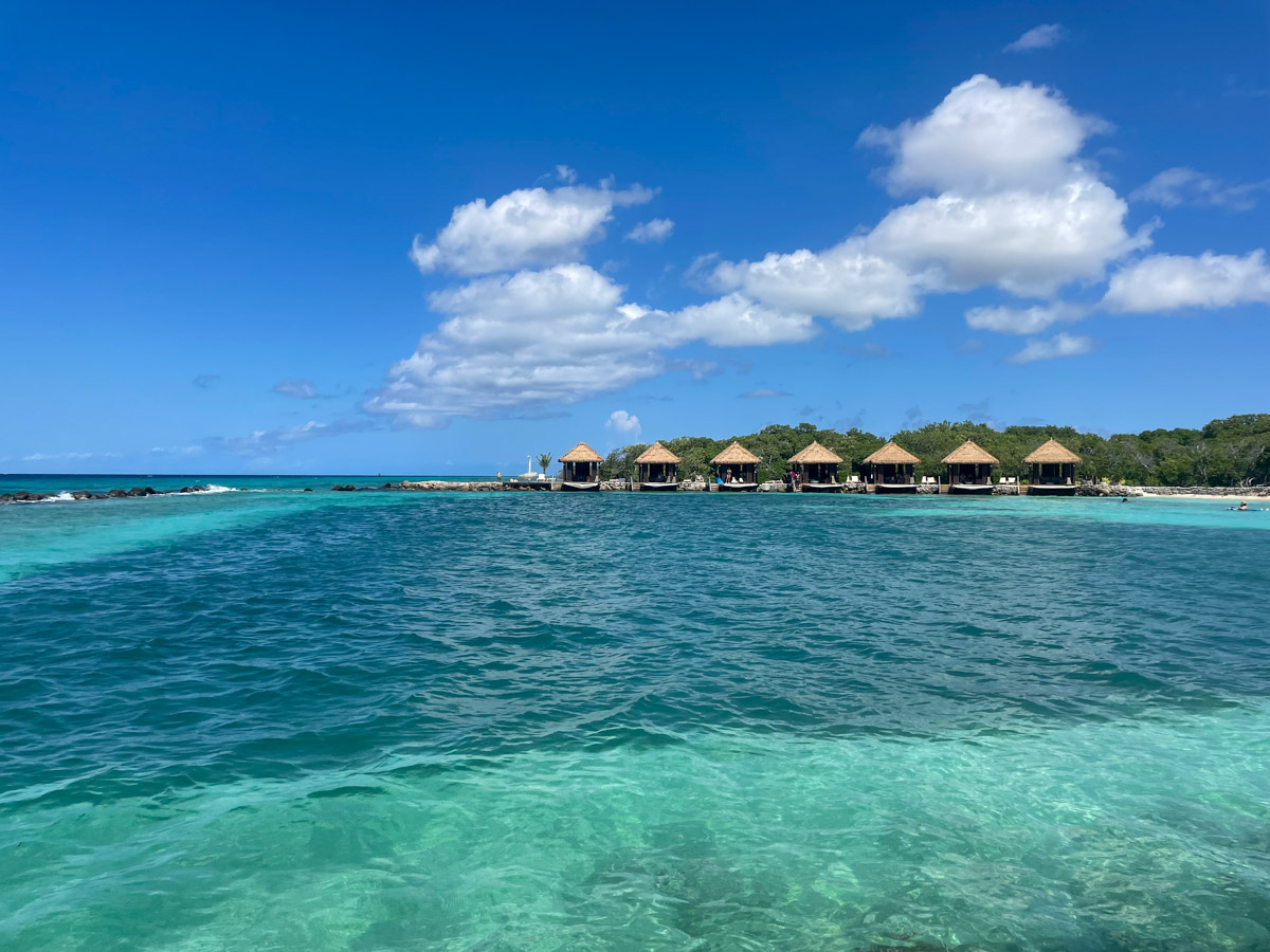 Clear turquoise waters near a line of overwater bungalows under a sunny sky. Renaissance Island in Aruba - an expensive spot but worth the visit. 